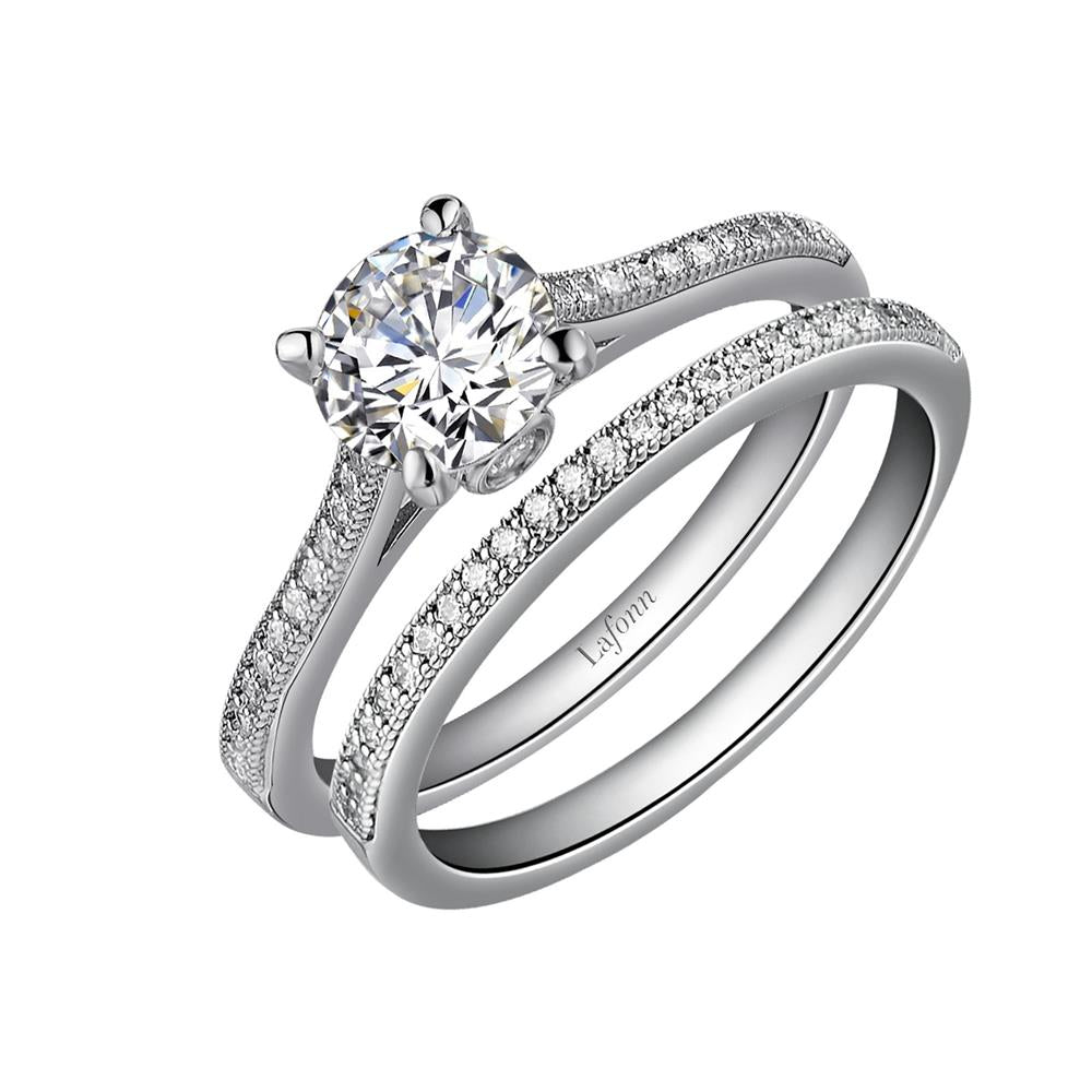 The Solitaire Wedding Ring set by Lafonn boasts a stunning silver engagement ring featuring a large, round-cut solitaire diamond atop a band encrusted with smaller diamonds. It is elegantly paired with a matching diamond-studded wedding band. Both rings are intricately crafted with meticulous attention to detail.