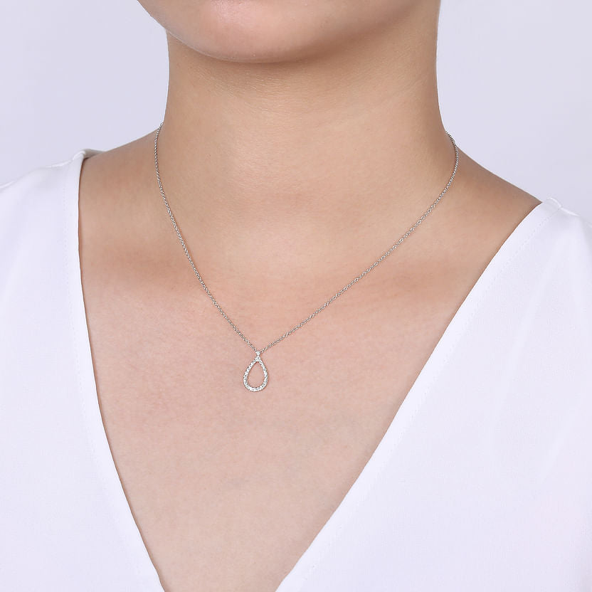 A person in a white V-neck top showcases the Gabriel & Co 14K White Gold Teardrop Diamond Pendant Necklace against a plain light gray background.