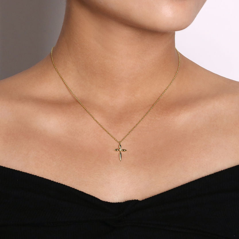 A woman in an off-the-shoulder black top showcases the 14K Yellow Gold Diamond Cross Pendant Necklace by Gabriel & Co, featuring a delicate chain and a simple diamond cross.