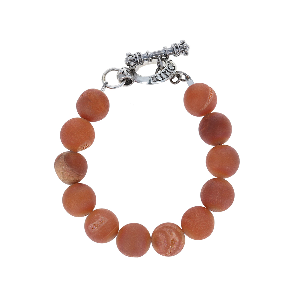 The King Baby 10mm peach druzy agate bracelet features round, matte orange beads and a silver toggle clasp, accented by a druzy bead, forming a circular pattern against a white background.