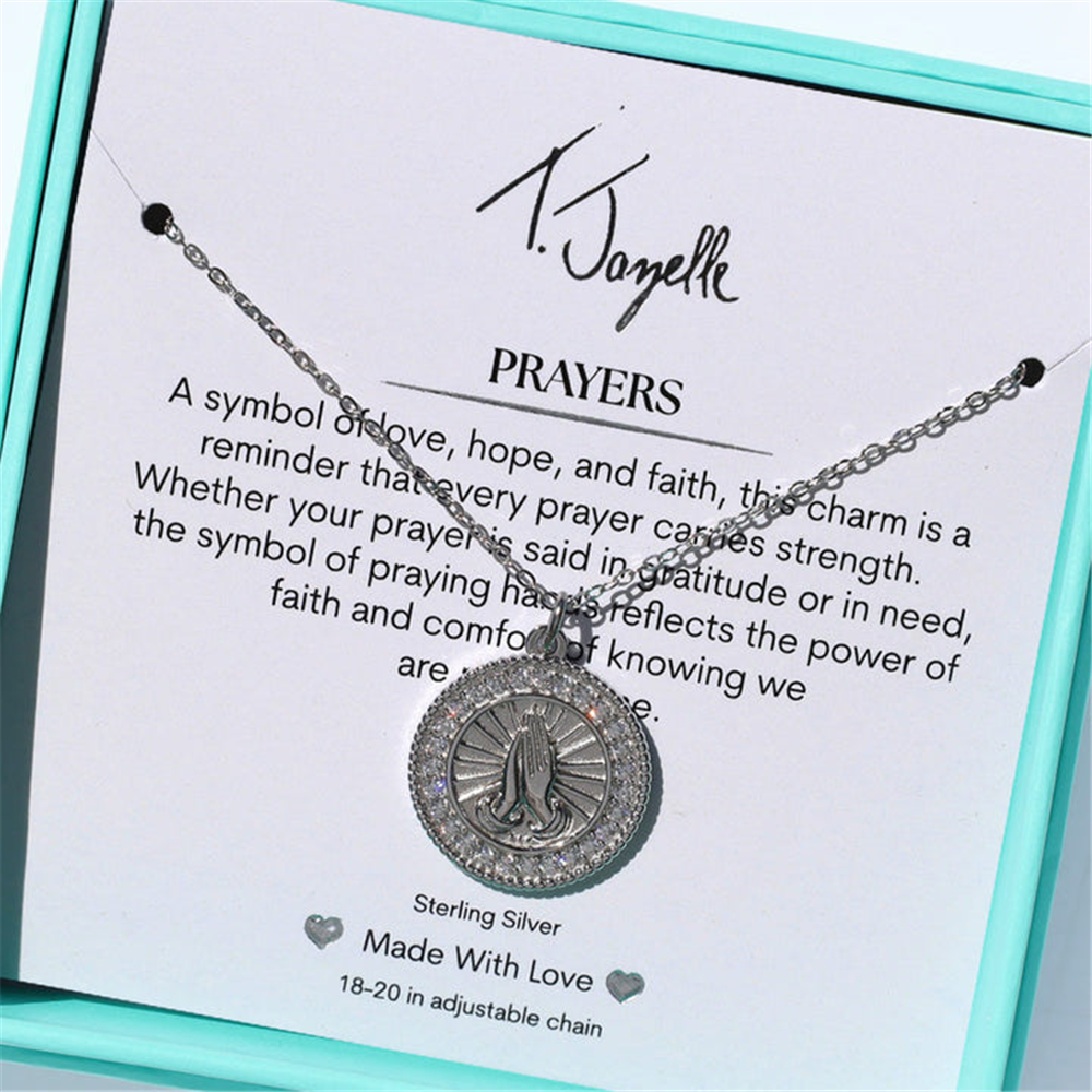The Prayers CZ Sterling Silver Charm Necklace by T Jazelle features a Praying Hands Charm, elegantly presented in a turquoise box with a card that reads: “PRAYERS. A symbol of love, hope, and faith..."—a beautiful piece of faith jewelry.