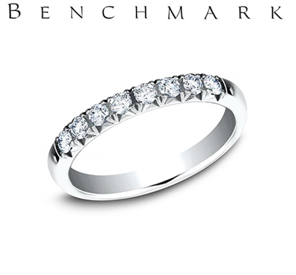 A 14K White Gold 0.32cts Lab Grown Diamond Butterfly Set Band from Benchmark Rings is displayed against a white background, adorned with a row of small, sparkling lab-grown diamonds on its top surface. The brand name "Benchmark Rings" appears in black capital letters above the ring.