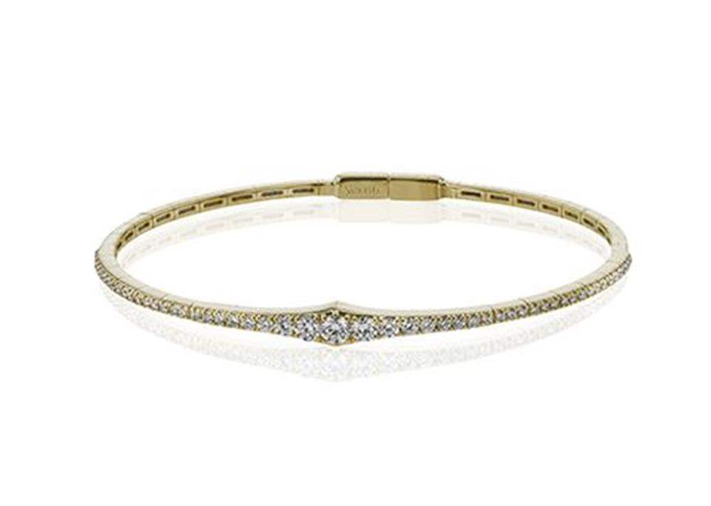 The Simon G. Tapered Diamond Bangle, crafted from 18K yellow gold, elegantly features small sparkling diamonds throughout its slender band. Displayed on a white background, this exquisite bracelet showcases the simple yet sophisticated design characteristic of Simon G.