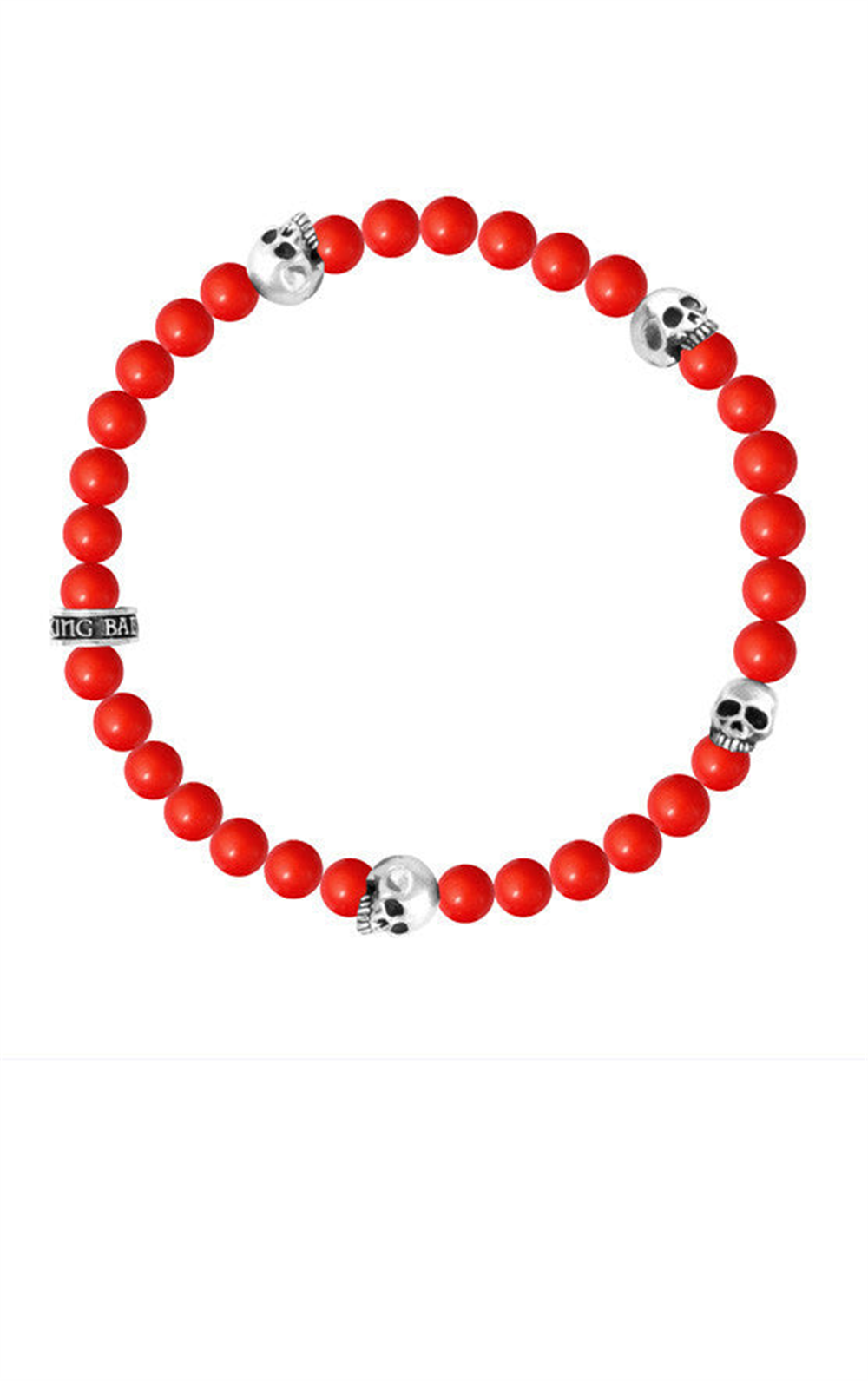 The 6mm red coral bead bracelet by King Baby features vibrant round beads and four silver skulls. One bead has engraved branding, offering a striking contrast, while the bracelet is elegantly arranged in a circle on a pristine white background.