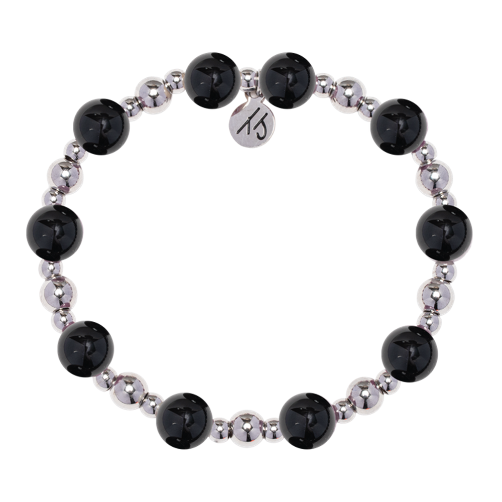 The Day by Day Collection – Onyx Gemstone Bracelet by T Jazelle features alternating large black onyx and smaller metallic silver beads with a round “KS” logo charm, making it perfect gratitude jewelry. Displayed on a white background.