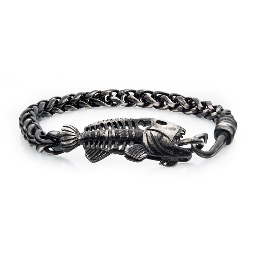 The INOX Gun Metal Plated Wheat Chain with Fishbone on Hook Clasp Bracelet features a robust, industrial design. Its centerpiece is a detailed fish skeleton, with the head and tail prominently showcased, seamlessly connected to a rugged wheat chain.