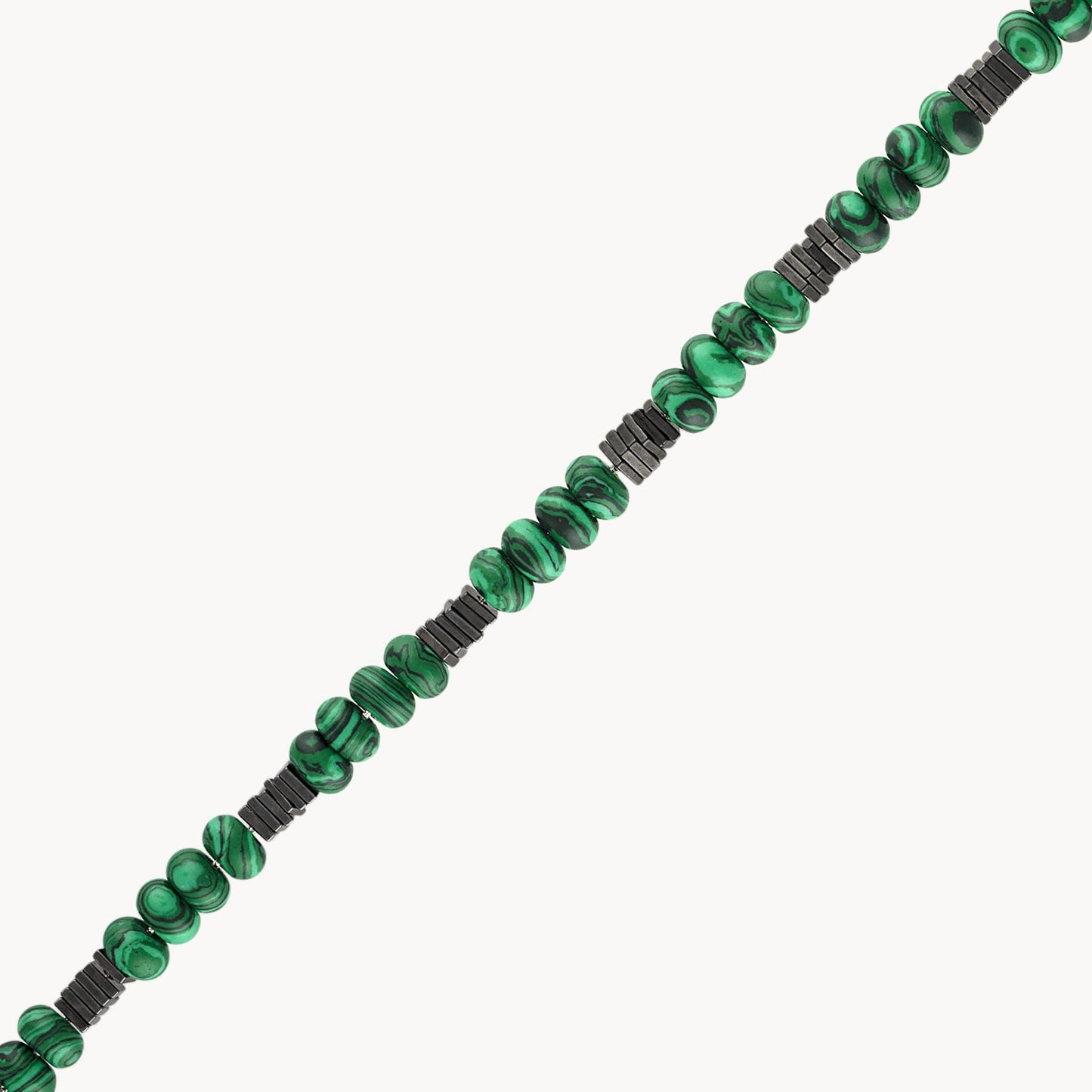 The luxurious Malachite Magnetic Bracelet by Bulova Watch Company features a strand of polished, marbled green Malachite beads interspersed with black cylindrical spacers, arranged diagonally against a plain background. The exquisite craftsmanship and the striking contrast between the gold plated sterling silver elements and the black spacers make this piece truly exceptional.