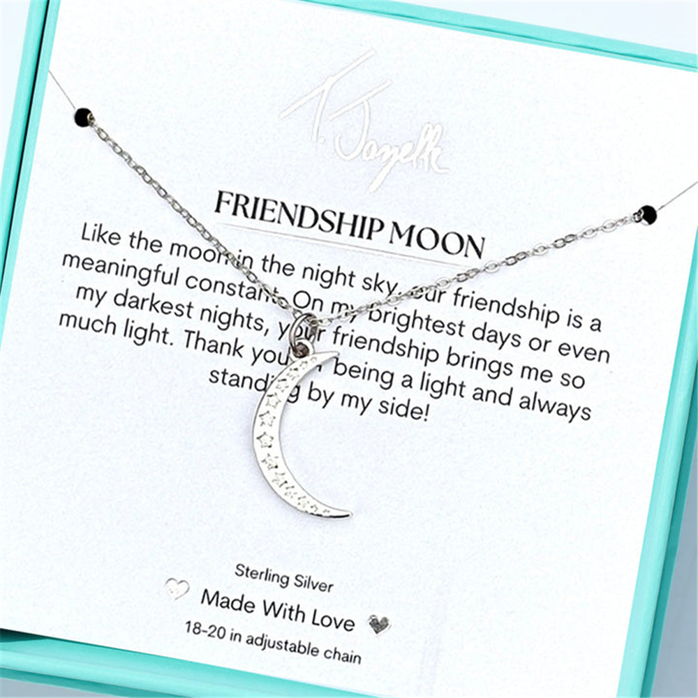 The Friendship Moon Sterling Silver Charm Necklace by T Jazelle rests on a "FRIENDSHIP MOON" card with a heartfelt message and comes elegantly presented in a turquoise jewelry box.