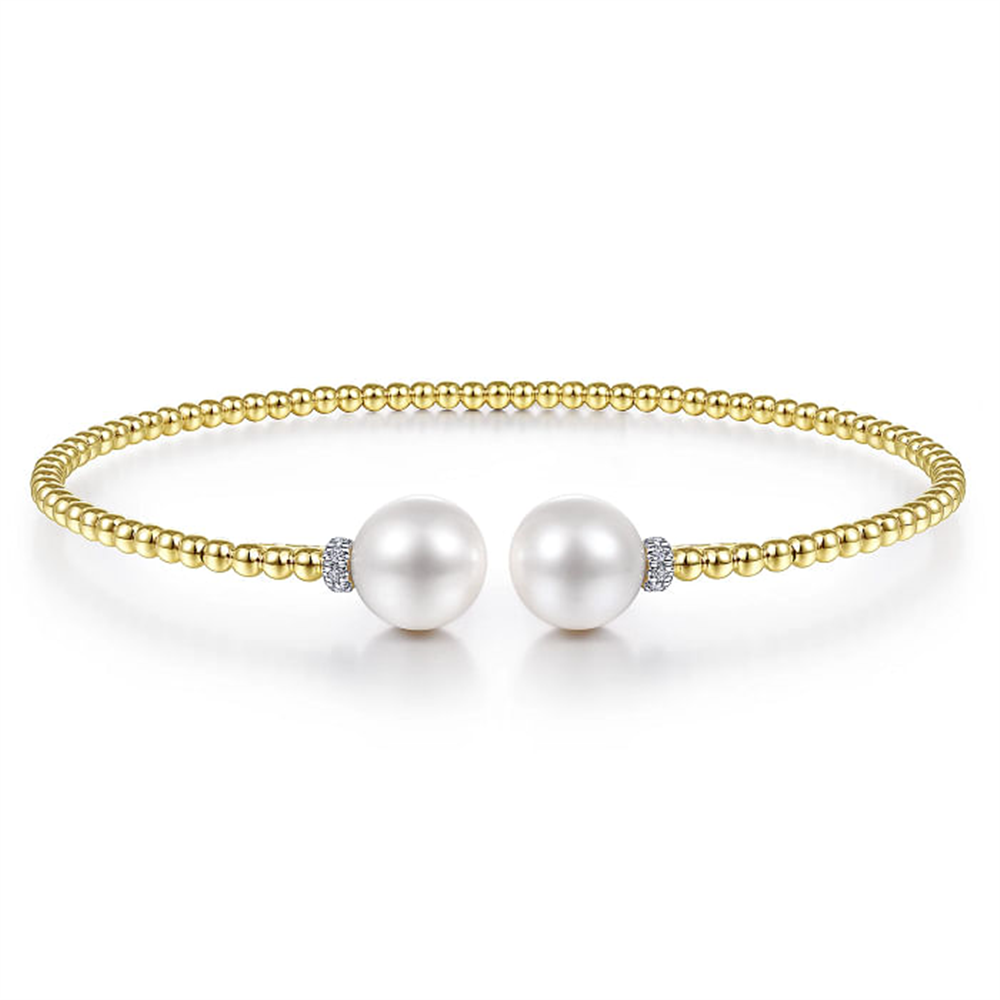 A 14K Yellow Gold Bujukan Diamond and Pearl Split Bangle from Gabriel & Co, featuring two large cultured pearls at the center, separated by small diamond accents. This gold beaded bracelet has a simple, elegant design and is shown against a white background.