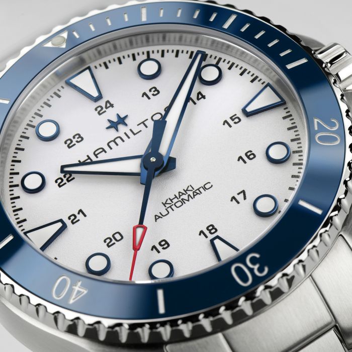 Close-up of the Hamilton Khaki Navy Scuba Automatic Watch showcasing a striking blue and white color scheme. This Hamilton timepiece features a blue ceramic bezel, luminous markers, and a white dial with a 24-hour inner ring. The red-tipped second hand adds a touch of contrast, making it perfect for maritime adventures.