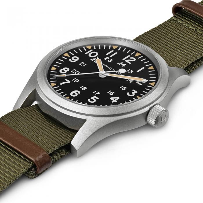 The Khaki Field Mechanical Watch by Hamilton features a silver case, black dial with white numerals, and both 12-hour and 24-hour markings. This 42mm timepiece comes with a green nylon strap accented with brown leather and operates on the dependable H-50 movement, complemented by a silver crown on the side.