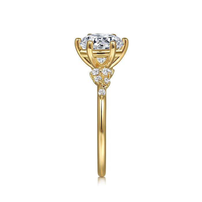Side view of the Gabriel & Co 14K Y floral band engagement ring with a large CZ center stone in a four-prong setting, accented by small diamonds on the intricate gold design. Displayed on a white background.