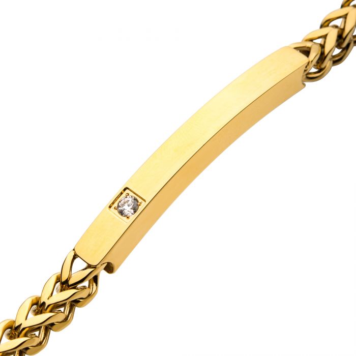 A close-up image of the 18K Gold Plated with Diamond Franco Chain Miami Cuban ID Bracelet by INOX showcases a rectangular plate in the center. The plate features a small diamond-like stone embedded on one side, adding a touch of elegance to the simple yet sophisticated design.