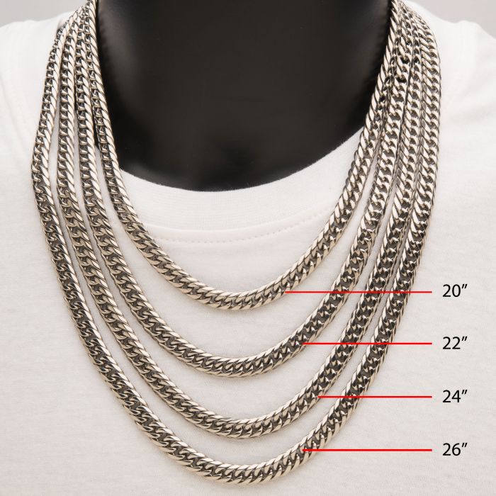 A black mannequin torso showcases a person wearing four different lengths of thick, stainless steel men's necklaces over a white shirt. Red labels mark the chain lengths: 20 inches (8mm Steel Dome Curb Chain by INOX), 22 inches, 24 inches, and 26 inches. These robust INOX curb chain necklaces add a solid touch to any outfit.