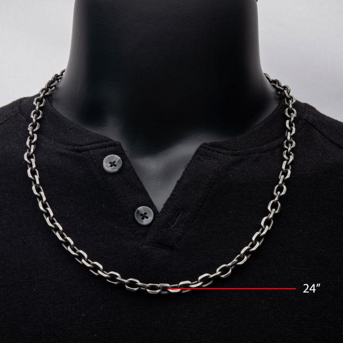 A black mannequin wears a black henley shirt with a 7mm Oxidized Steel Knife Edge Link Chain measuring 24 inches. The shirt has two buttons on the chest, and the chain's length is indicated with a red line and text.