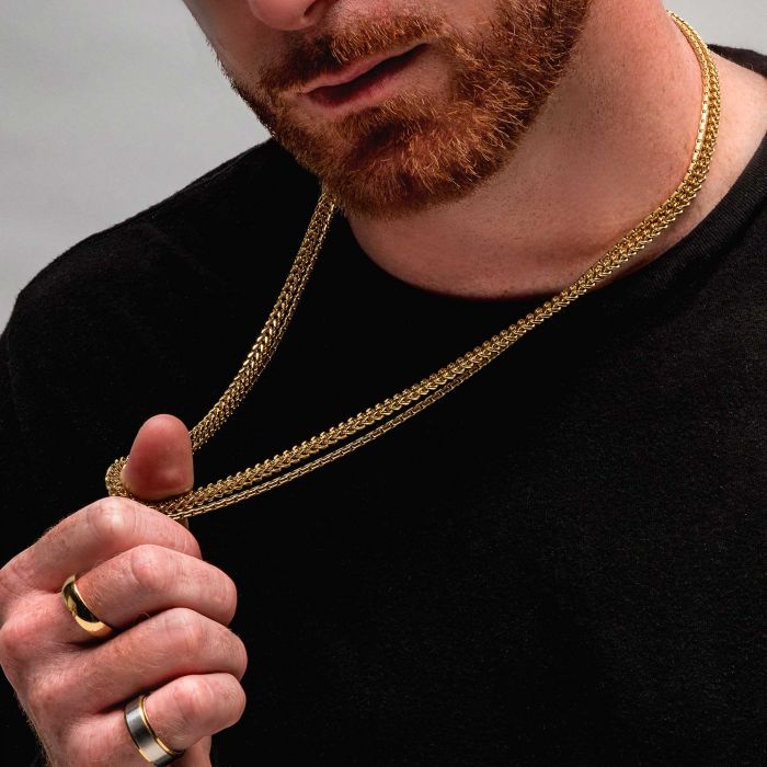 A person with a red beard wearing a black shirt holds up an INOX 3mm 18K Gold Plated Boston Link Chain Necklace, measuring 24 inches. They have two gold rings on their fingers, and their face is partially visible in the bottom half of the frame.