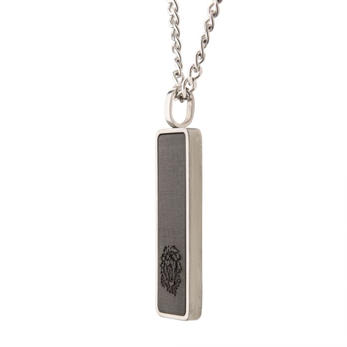 A close-up of the Carbon Fiber & Steel Dog Tag Pendant by INOX, showcasing its rectangular charm with a dark carbon fiber inlay that features an engraved emblem of a stylized animal head. The pendant is suspended from a sturdy 24-inch steel curb chain.