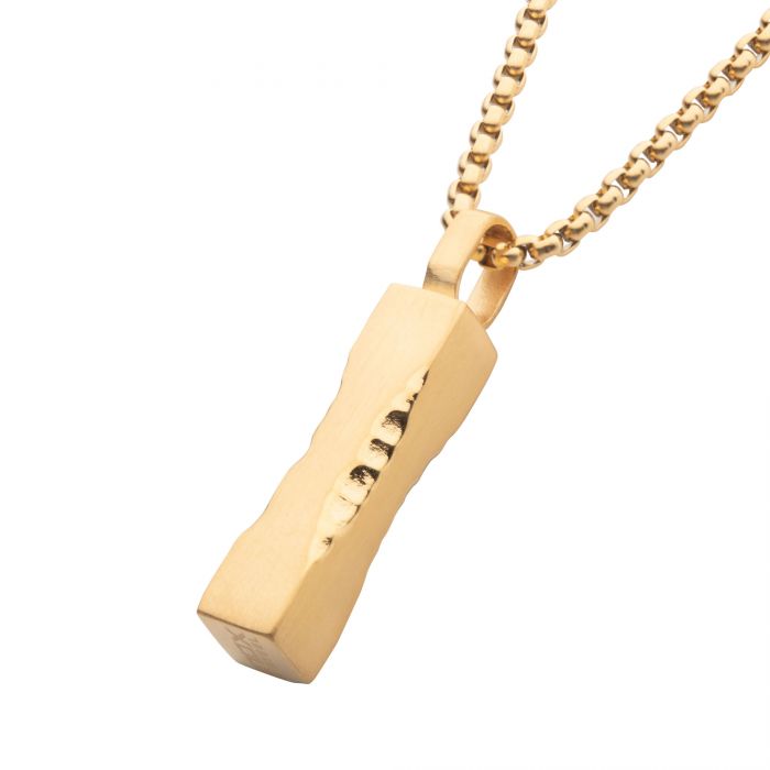 A gold necklace featuring a rectangular, textured pendant hangs from a matching chain. The Matte 18K Gold IP Chiseled Engravable Drop Pendant by INOX has an irregular, hammered design on the surface, adding a unique and artisanal feel to the piece.