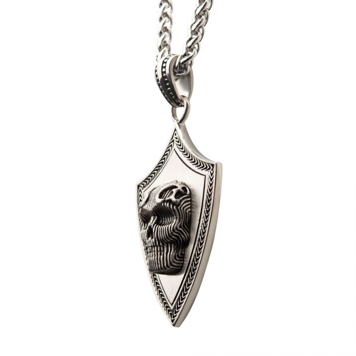 An intricate 3D skull pendant, treated with a black oxidized matte finish, hangs from a matching black oxidized wheat chain. This striking piece, crafted by INOX, features remarkable detailing that enhances its bold and distinctive look.