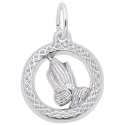 The Praying Hands Charm by Rembrandt Charms features a pair of praying hands in sterling silver, encased in a circular, textured border with a small loop at the top for easy attachment to a chain or bracelet. This elegant piece is showcased against a plain white background.