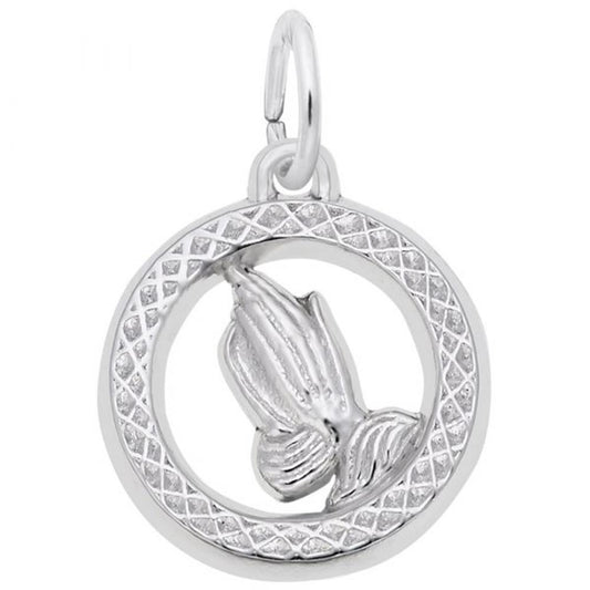 The Praying Hands Charm by Rembrandt Charms features a pair of praying hands in sterling silver, encased in a circular, textured border with a small loop at the top for easy attachment to a chain or bracelet. This elegant piece is showcased against a plain white background.