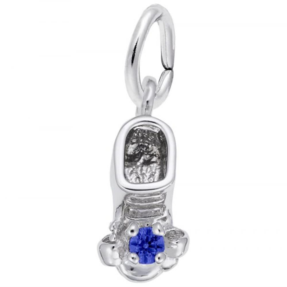 The September Baby Shoe Charm from Rembrandt Charms is a small, sterling silver charm shaped like a shoe, featuring a blue gemstone at the toe. It includes a circular loop for easy threading onto a necklace or bracelet.
