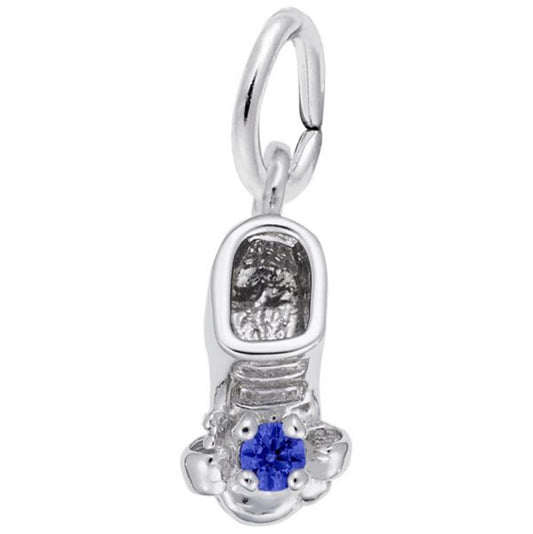 The September Baby Shoe Charm from Rembrandt Charms is a small, sterling silver charm shaped like a shoe, featuring a blue gemstone at the toe. It includes a circular loop for easy threading onto a necklace or bracelet.