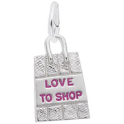 The Rembrandt Charms Shopping Bag Charm features the text "LOVE TO SHOP" in pink letters on the front. This sterling silver piece has a loop at the top for attaching to a bracelet or necklace, and boasts a detailed texture resembling a woven pattern, making it an eye-catching accessory.