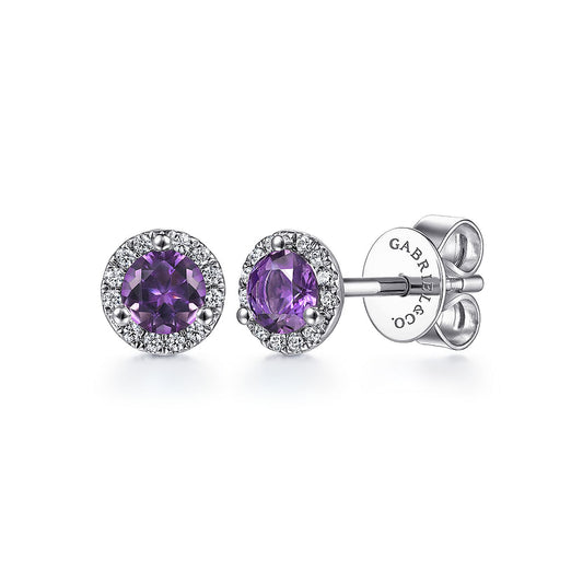 Gabriel & Co 14K White Gold Amethyst and Diamond Halo Stud Earrings feature round purple amethysts at the center, surrounded by a sparkling diamond halo, and secured with butterfly backings.
