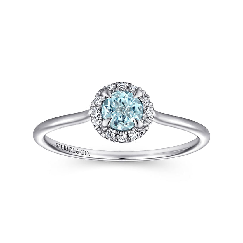 The Gabriel & Co 14K White Gold Aquamarine and Diamond Halo Ring features a round blue aquamarine center, sparkling diamond halo, and a slim band engraved with "GABRIEL&CO." on one side.
