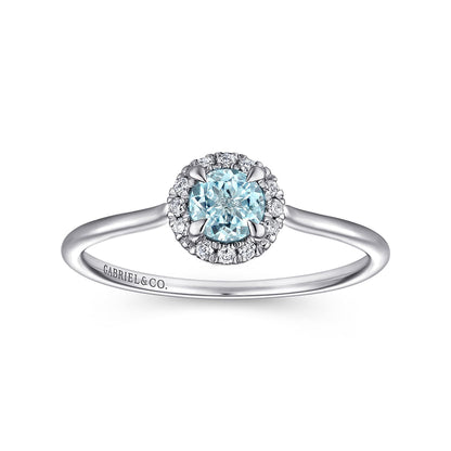 The Gabriel & Co 14K White Gold Aquamarine and Diamond Halo Ring features a round blue aquamarine center, sparkling diamond halo, and a slim band engraved with "GABRIEL&CO." on one side.