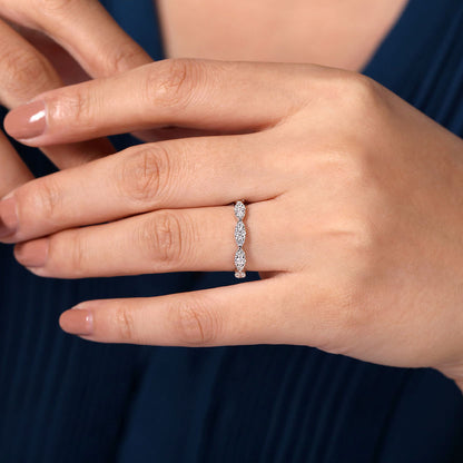 A hand with neatly manicured nails wears the Gabriel & Co 14K White Gold Diamond Cluster Marquis Station Ring, featuring a row of sparkling marquise diamonds in a thin, stackable band, with a blue garment visible in the background.