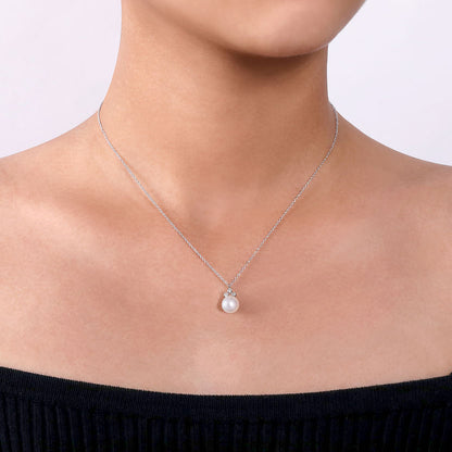 A person wears the Gabriel & Co 14K White Gold Diamond and Pearl Pendant Necklace, showcasing a single cultured pearl, paired with an off-the-shoulder black top against a light background.