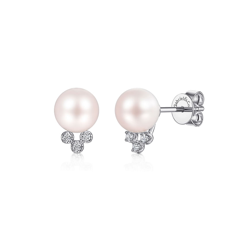 The 14K White Gold Diamond and Pearl Stud Earrings by Gabriel & Co feature round cultured pearls each accented with three small diamonds below, and visible earring backs stamped with the brand name.