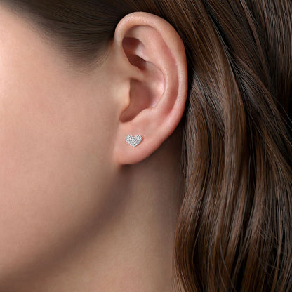 Close-up of a woman with straight brown hair wearing Gabriel & Co 14K White Gold Heart Shaped Pave Diamond Stud Earrings.