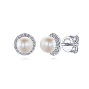 The 14K White Gold Round Diamond Halo Pearl Stud Earrings by Gabriel & Co feature round white pearls encircled by sparkling diamonds and secure butterfly backings.
