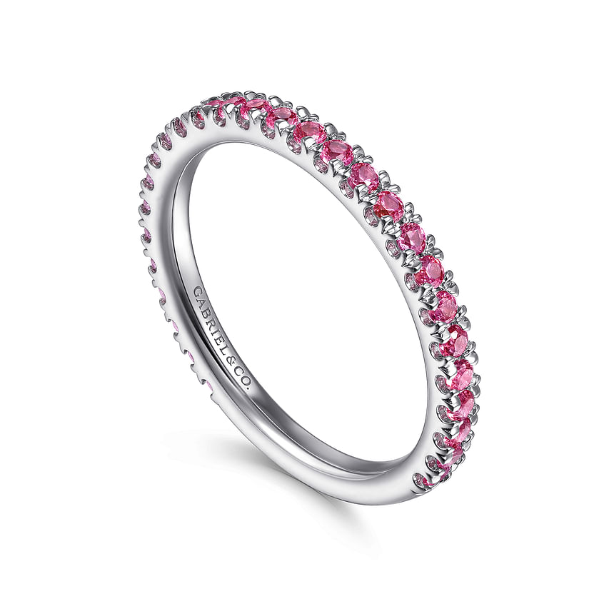 The 14K White Gold Ruby Stackable Ring by Gabriel & Co features vibrant pink gemstones along the band and is engraved with the brand name. Presented by Avonlea Jewelers against a white background.