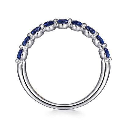 The 14K White Gold Sapphire Stackable Ring by Gabriel & Co showcases a row of oval blue sapphires set on the upper half of the silver-tone band, displayed against a white background.