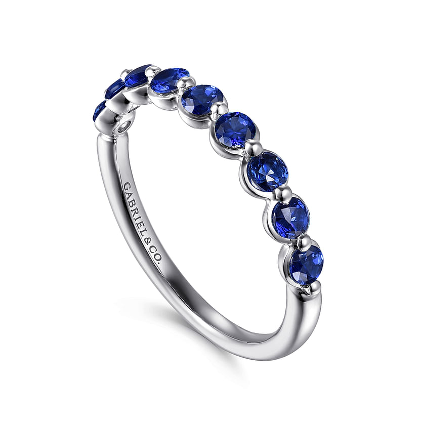 The 14K White Gold Sapphire Stackable Ring by Gabriel & Co features a row of round blue gemstones set along the top and is displayed on a white background.