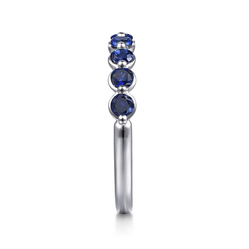 A side view of the Gabriel & Co 14K White Gold Sapphire Stackable Ring displays five round blue sapphires set in a vertical row along the white gold band, shown against a white background.