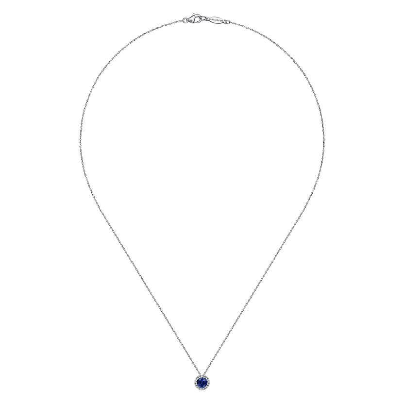 The Gabriel & Co 14K White Gold Sapphire and Diamond Halo Pendant Necklace showcases a small round sapphire pendant encircled by a subtle diamond halo.