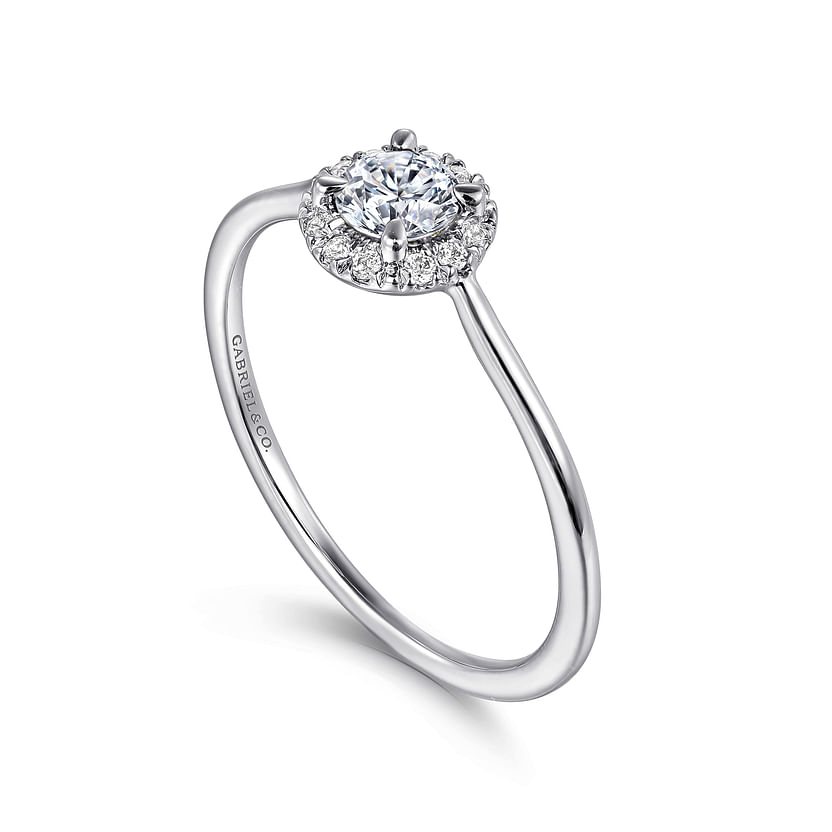 A 14K white gold promise ring by Gabriel & Co, featuring a round white sapphire center, a sparkling diamond halo, and set on a thin, slightly curved band.