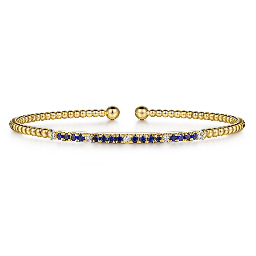 The Gabriel & Co 14K Yellow Gold Bujukan Diamond and Blue Sapphire Split Bangle features beaded detailing, a central bar with alternating sapphires and diamonds, and two round gold end caps.