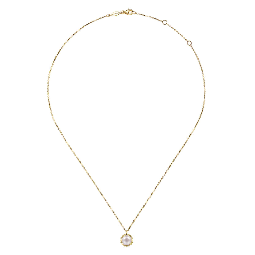 The 14K Yellow Gold Bujukan Pearl Pendant Necklace by Gabriel & Co features a round white pearl in a scalloped gold frame, shown on a white background. Discover timeless elegance in the Bujukan Collection.