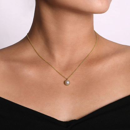 A woman in an off-shoulder black top showcases the Gabriel & Co 14K Yellow Gold Bujukan Pearl Pendant Necklace, featuring a circular pearl pendant, against a plain light background.