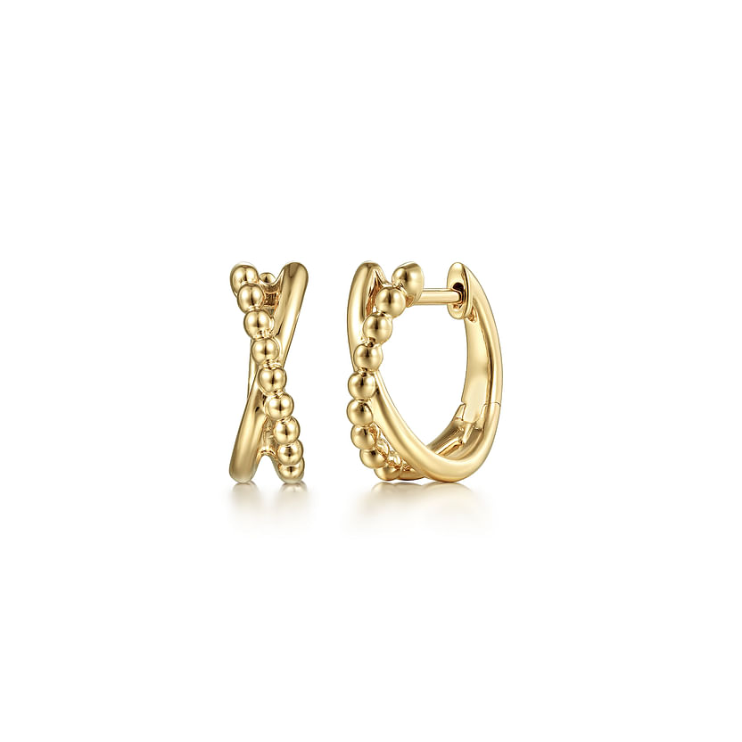 A pair of 14K Yellow Gold Bujukan Twisted Huggie Earrings by Gabriel & Co—one with a beaded design, the other smooth—are displayed elegantly on a white background.