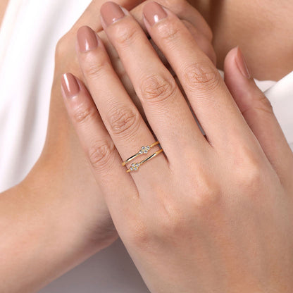 A hand with neatly manicured nails wears two Gabriel & Co 14K Yellow Gold Diamond Easy Stackable Rings, each featuring a sparkling natural diamond, one hand gently resting atop the other.