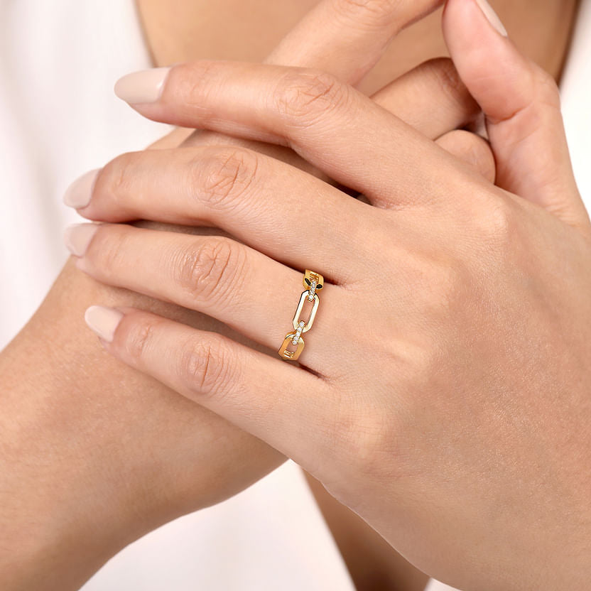 A close-up shows hands with neatly manicured nails wearing the Gabriel & Co 14K Yellow Gold Diamond Link Chain Ladies Ring, set against a softly blurred background.