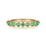 The 14K Yellow Gold Emerald Stackable Ring by Gabriel & Co showcases a row of round green emeralds along the band, with "GABRIEL&CO." engraved inside.