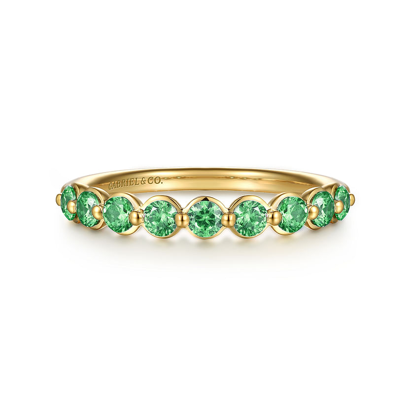 The 14K Yellow Gold Emerald Stackable Ring by Gabriel & Co showcases a row of round green emeralds along the band, with "GABRIEL&CO." engraved inside.